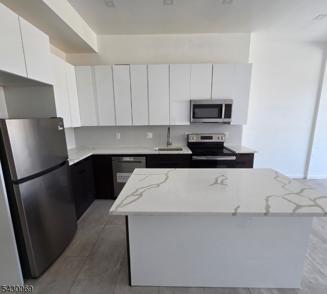 30 Howe Avenue, Unit 303 Passaic, NJ 07055 - Photo 3 of 11 a kitchen with a refrigerator and a stove
