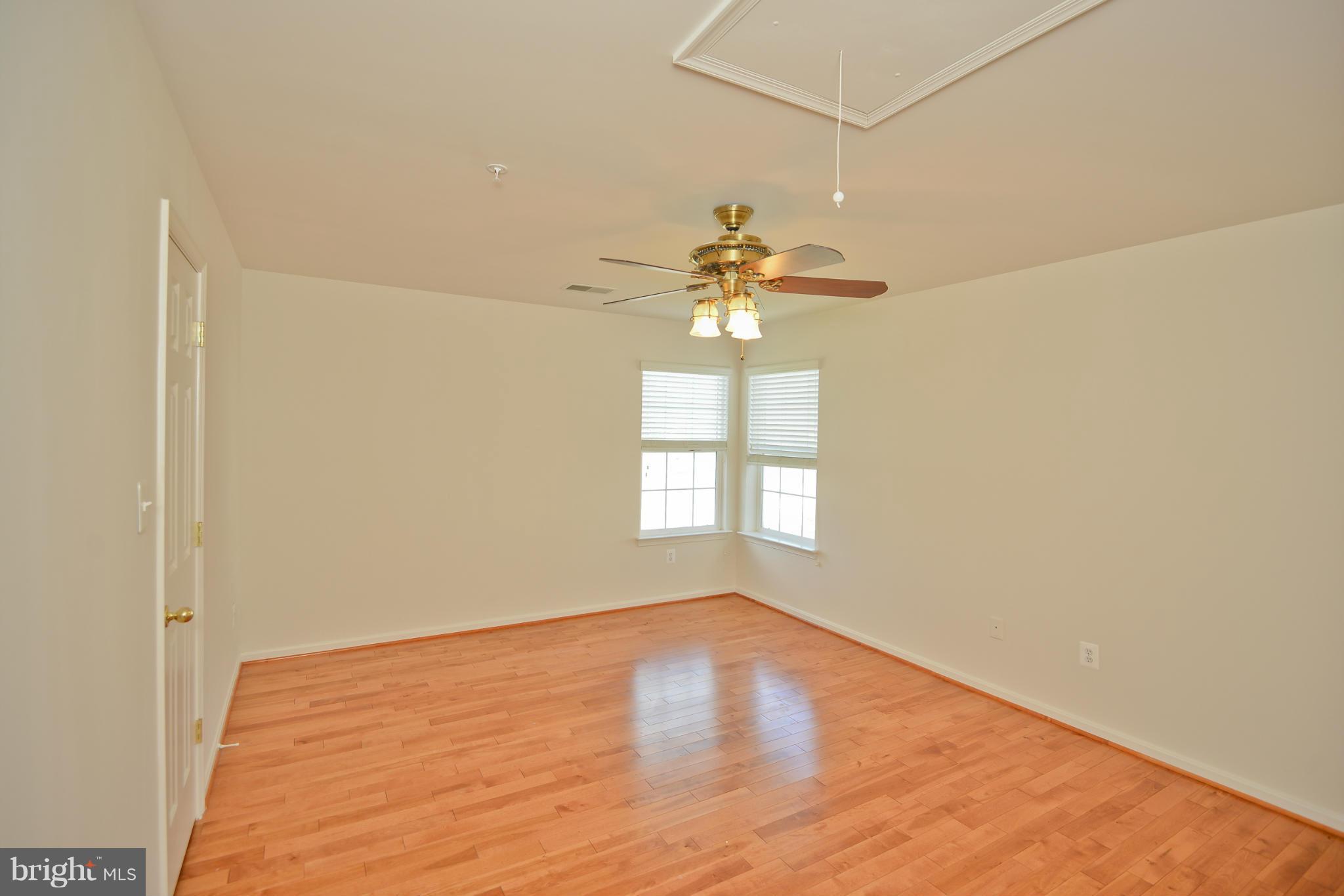 14618 Bubbling Spring Road Boyds, MD 20841 - Photo 14 of 26 an empty room with a chandelier fan and windows