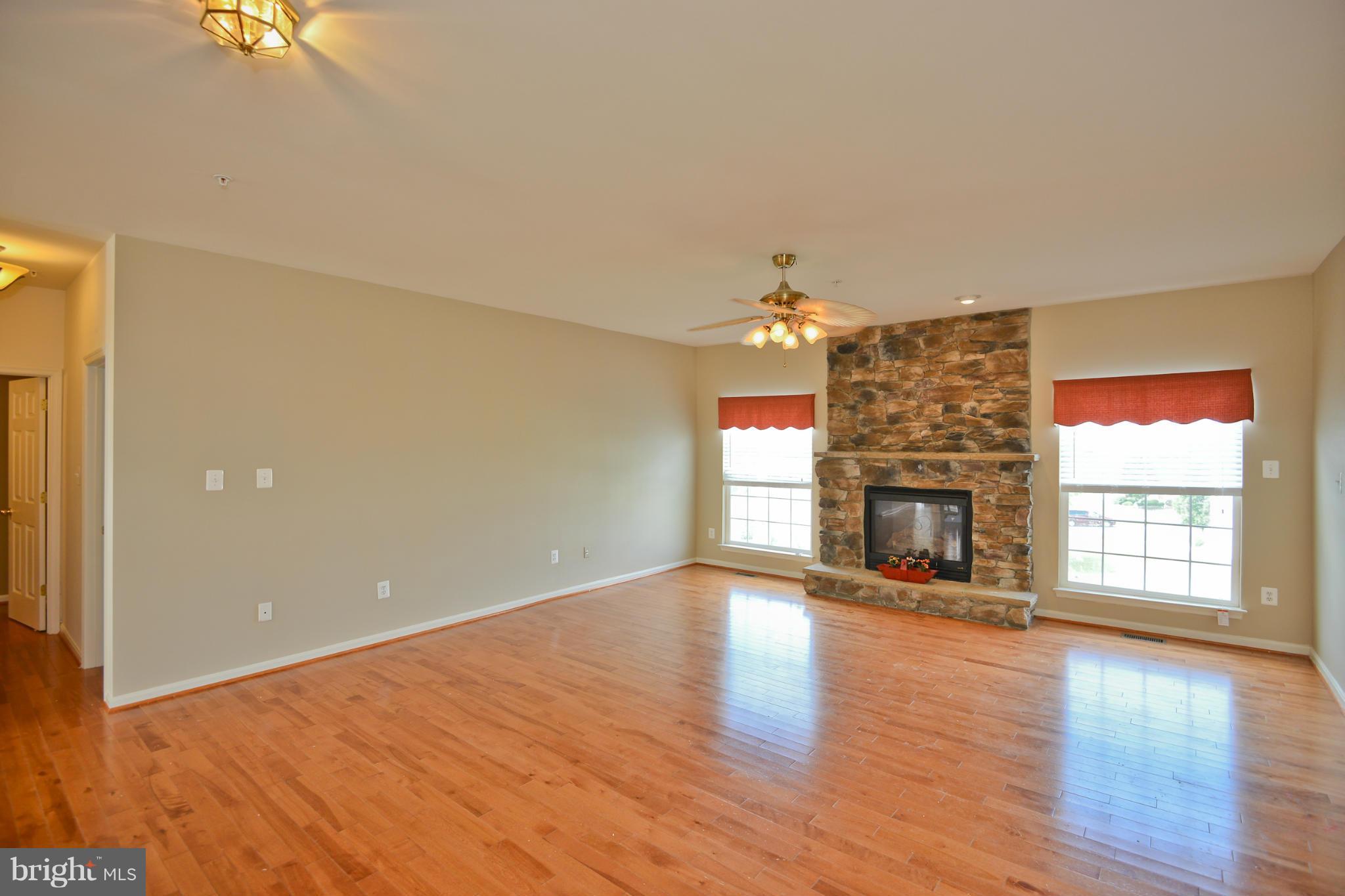 14618 Bubbling Spring Road Boyds, MD 20841 - Photo 6 of 26 an empty room with wooden floor fireplace and windows