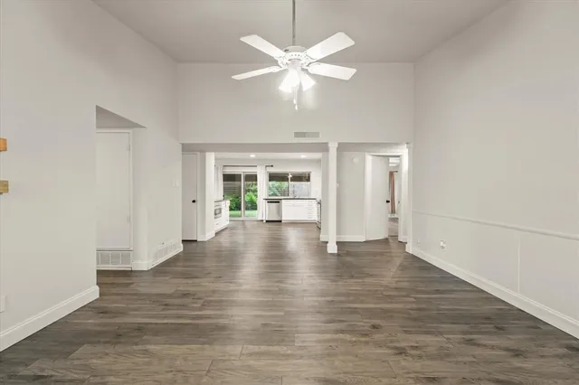 an empty room with wooden floor fireplace and windows