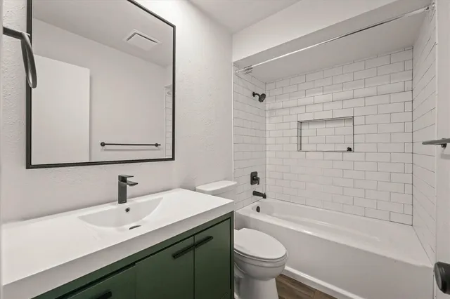 a view of an empty room with wooden floor and a ceiling fan