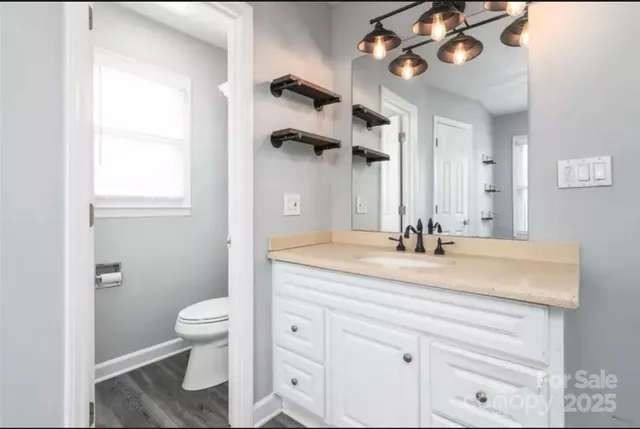 a bathroom with a granite countertop sink a toilet and a mirror