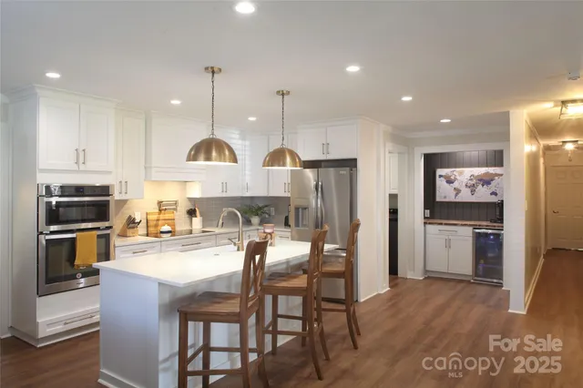 a kitchen with refrigerator a stove and chairs with wooden floor