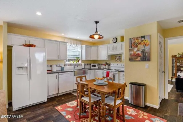 a kitchen with stainless steel appliances granite countertop a dining table chairs refrigerator and sink