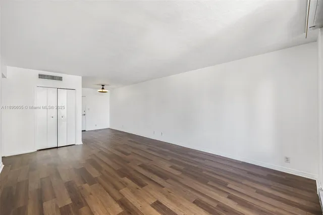 a view of empty room with wooden floor