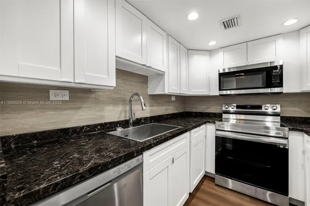 a kitchen with granite countertop a sink stainless steel appliances and cabinets