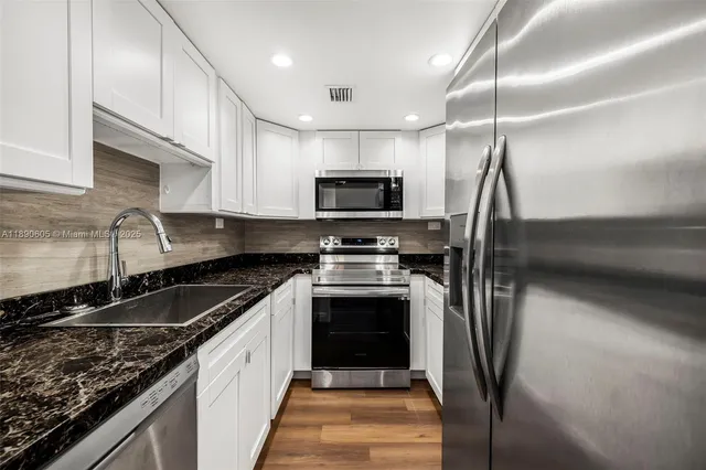 a kitchen with stainless steel appliances granite countertop a stove a sink and a microwave