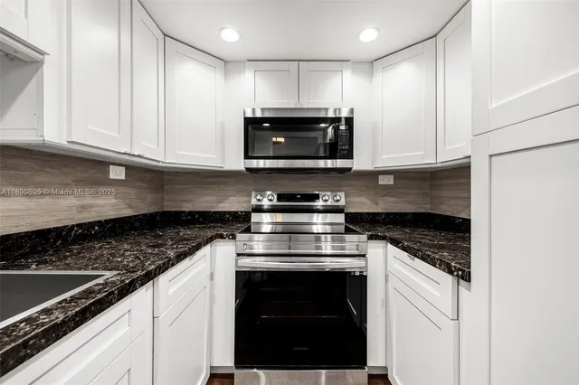 a kitchen with granite countertop a stove and a microwave