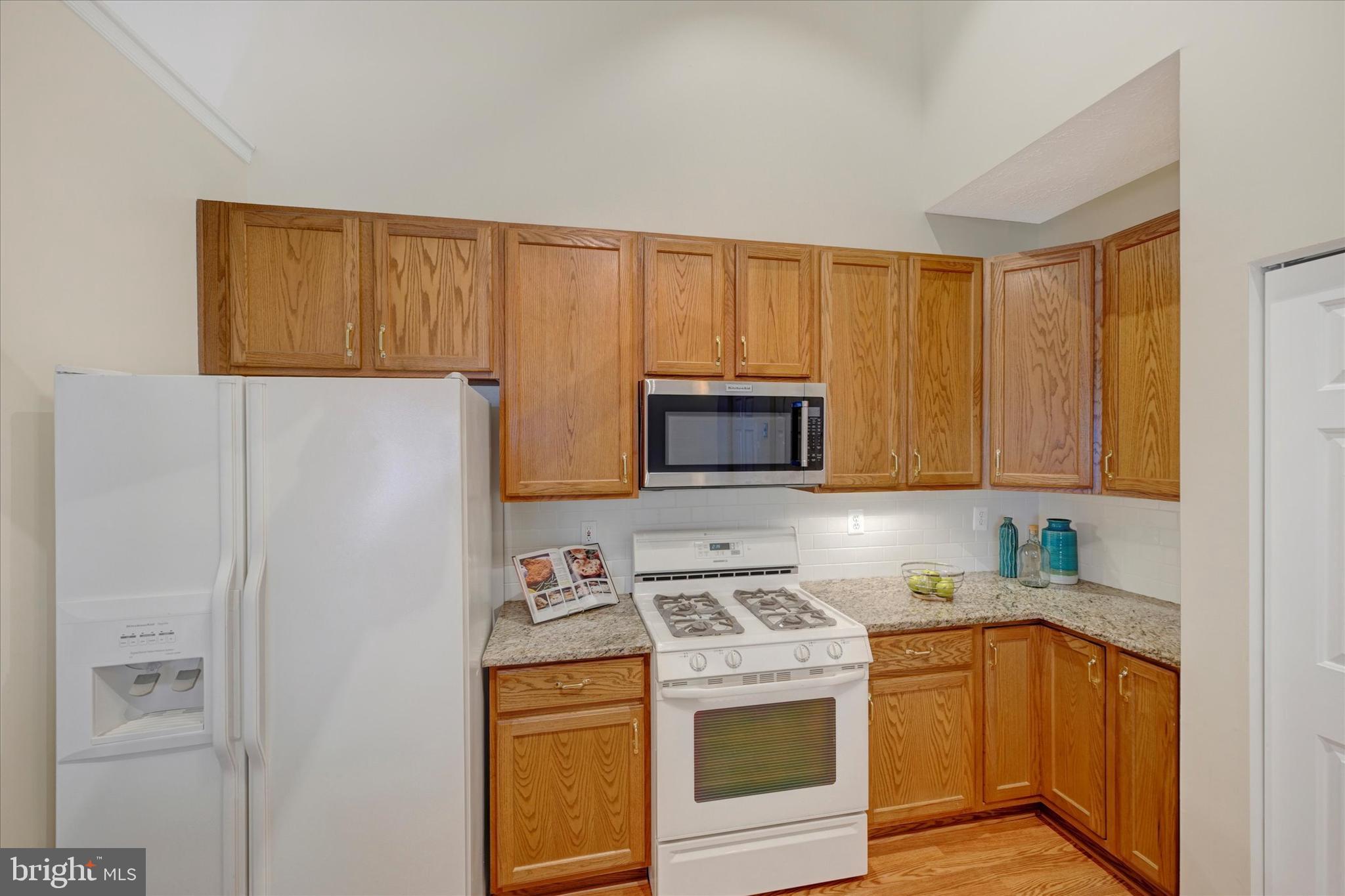 9606 Haven Farm Road, Unit 9606M Perry Hall, MD 21128 - Photo 14 of 49 a kitchen with stainless steel appliances granite countertop a refrigerator a stove a sink and a white cabinets with wooden floor