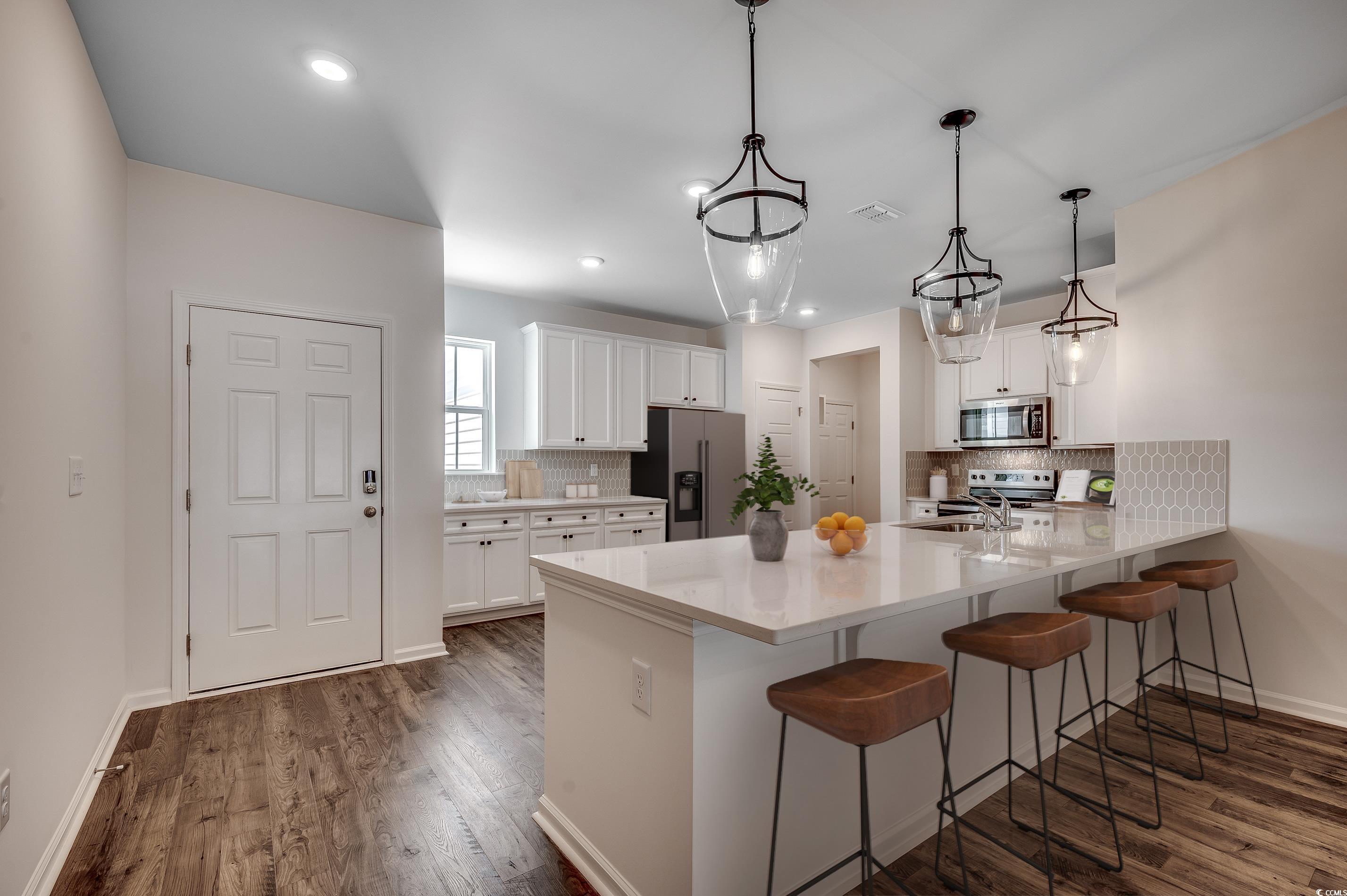 133 Buckingham Drive Loris, SC 29569 - Photo 2 of 17 Kitchen with a kitchen breakfast bar, white cabinetry, tasteful backsplash, appliances with stainless steel finishes, and recessed lighting