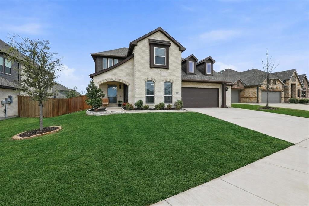Brick and stucco exterior featuring a covered entry, arched windows, and a two-car garage