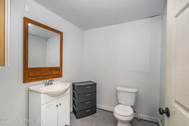 a bathroom with a toilet a sink a mirror and a window
