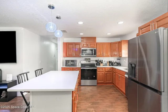 a kitchen with stainless steel appliances kitchen island granite countertop a refrigerator a stove top oven a sink and dishwasher