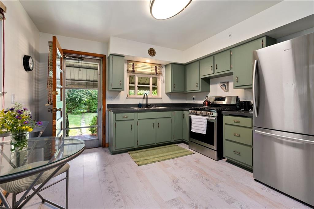 3755 Merle Street Pittsburgh, PA 15204 - Photo 8 of 15 Kitchen showcasing stainless steel appliances, sage green cabinets, and concrete countertops.