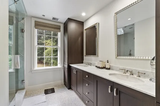 a bathroom with a double vanity sink mirror and shower