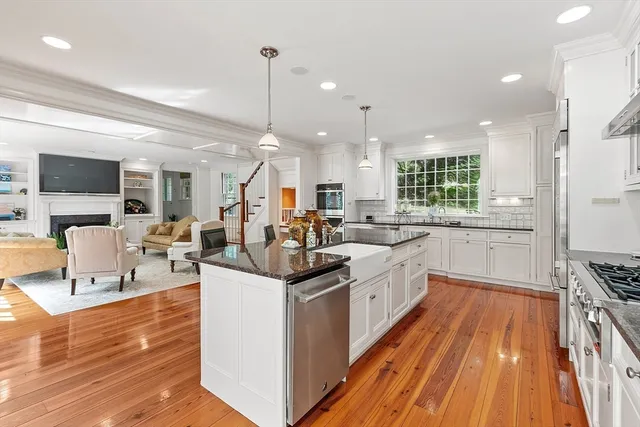 a kitchen with stainless steel appliances granite countertop a stove top oven a sink dishwasher a dining table and chairs with wooden floor