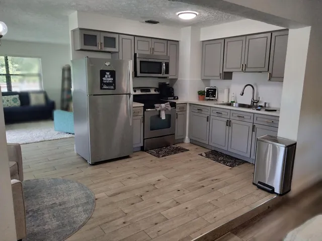 a kitchen with stainless steel appliances granite countertop a stove top oven a sink and a refrigerator