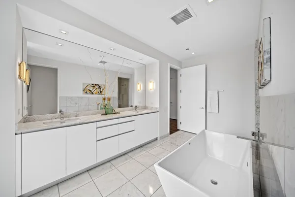 a spacious bathroom with a granite countertop sink mirror and bathtub