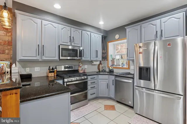 a kitchen with stainless steel appliances granite countertop a refrigerator stove microwave and sink