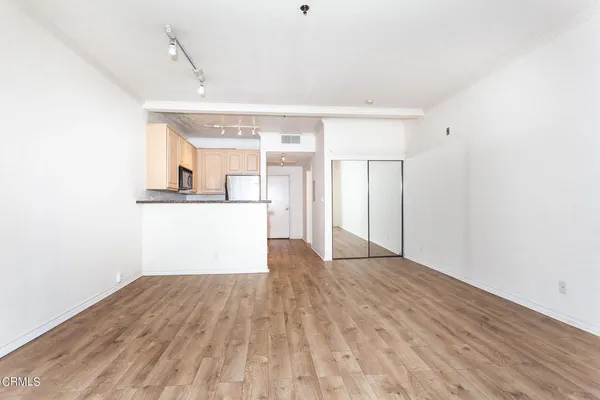 a view of a kitchen with wooden floor and white cabinets
