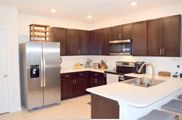 a kitchen with a sink a refrigerator and a stove top oven with wooden cabinets