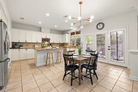 a kitchen with stainless steel appliances granite countertop a stove a sink a dining table and chairs