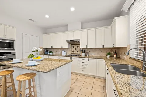 a kitchen with stainless steel appliances granite countertop a sink stove refrigerator and cabinets