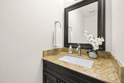 a bathroom with a granite countertop sink and a mirror