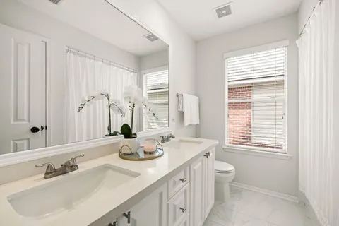 a bathroom with double vanity sinks a toilet and a mirror