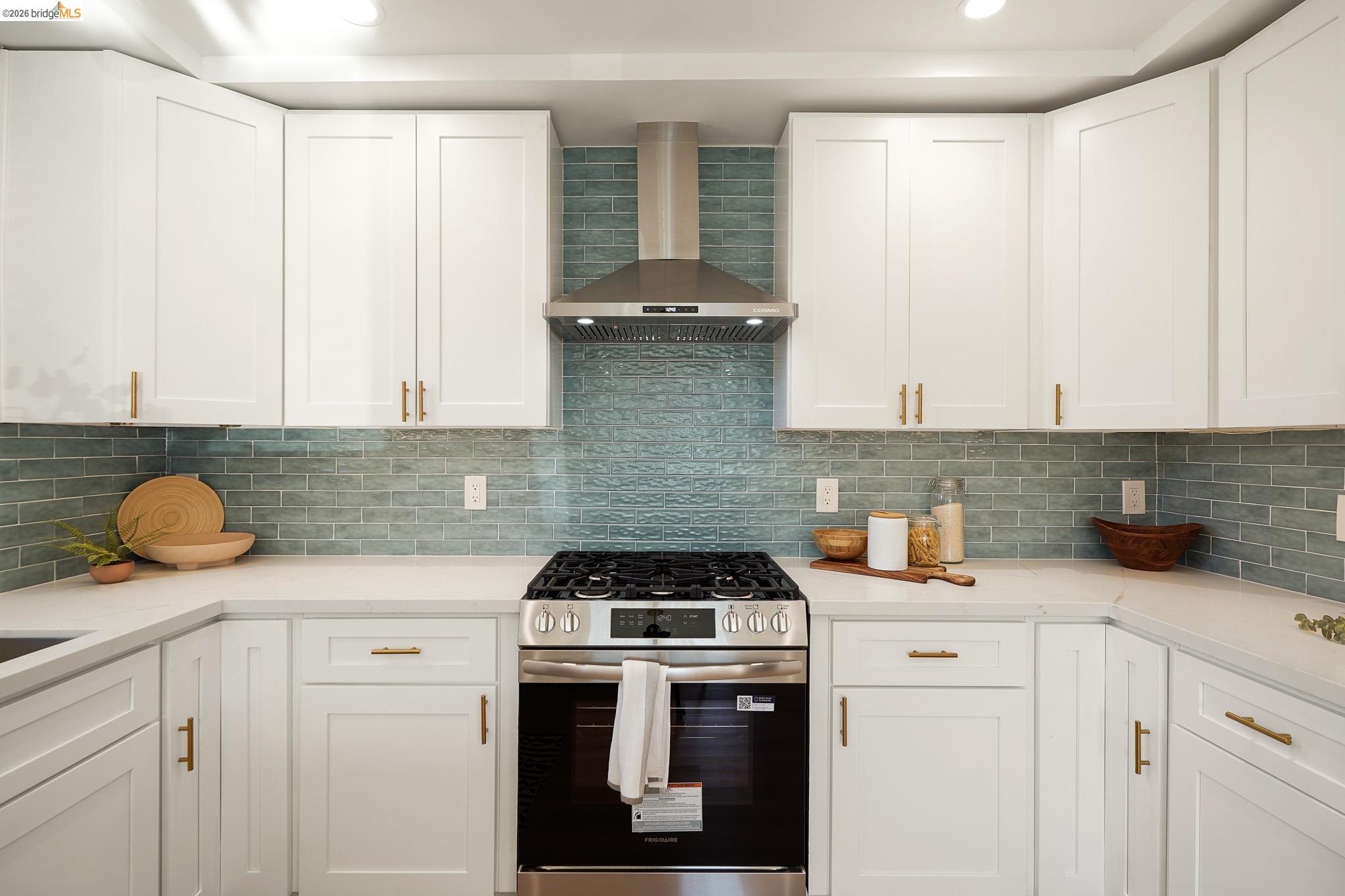 2151 Santa Rita Street Oakland, CA 94601 - Photo 12 of 46 Kitchen with stainless steel gas range oven, wall chimney exhaust hood, white cabinets, tasteful backsplash, and light stone counters