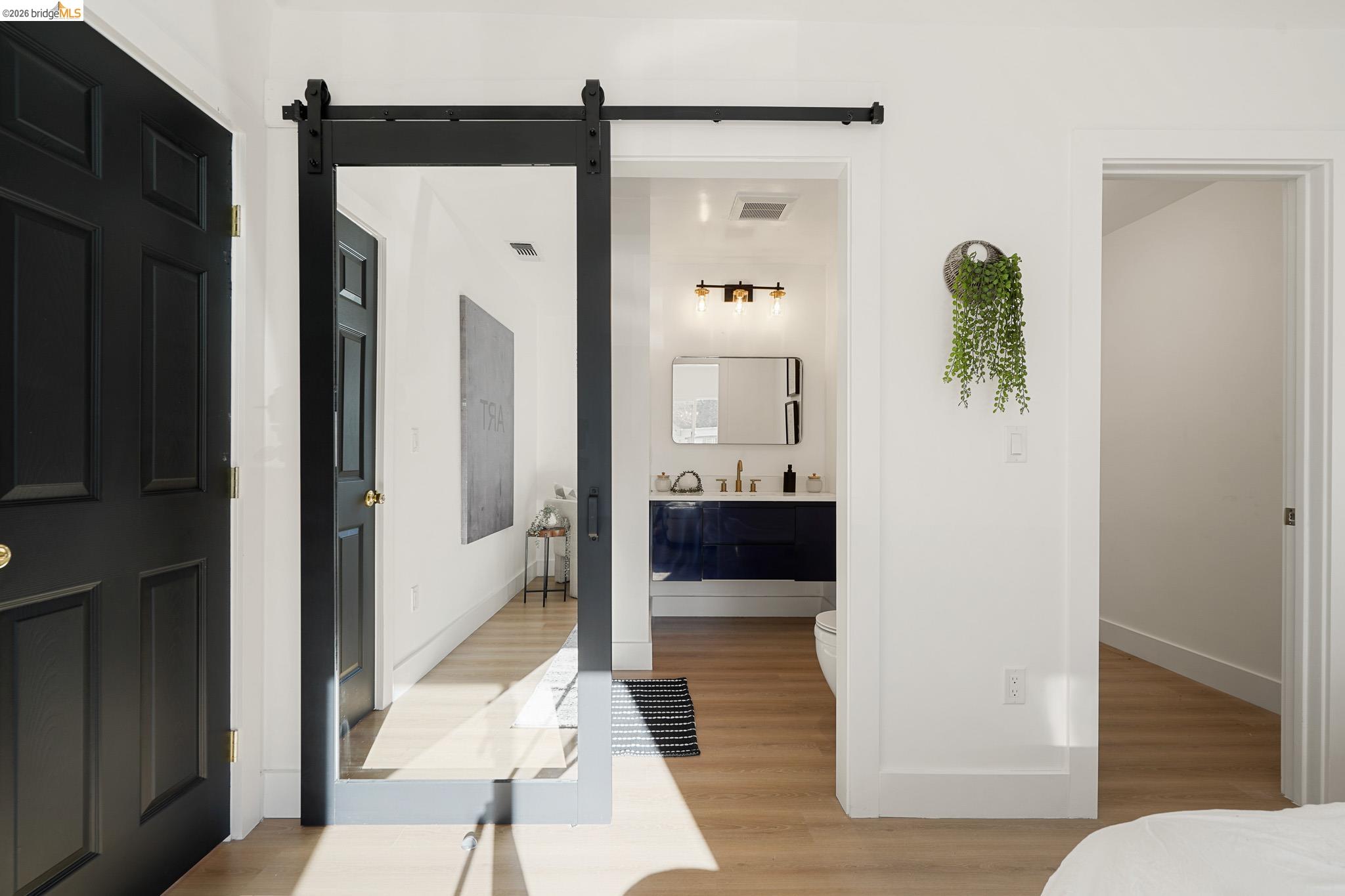 2151 Santa Rita Street Oakland, CA 94601 - Photo 18 of 46 Bedroom featuring light wood-type flooring, a barn door, and ensuite bath