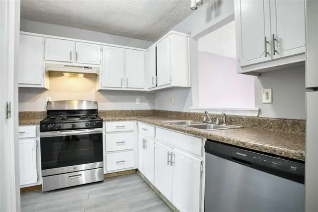a kitchen with granite countertop cabinets stainless steel appliances and a counter space