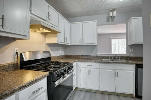 a view of a kitchen with wooden floor and cabinets