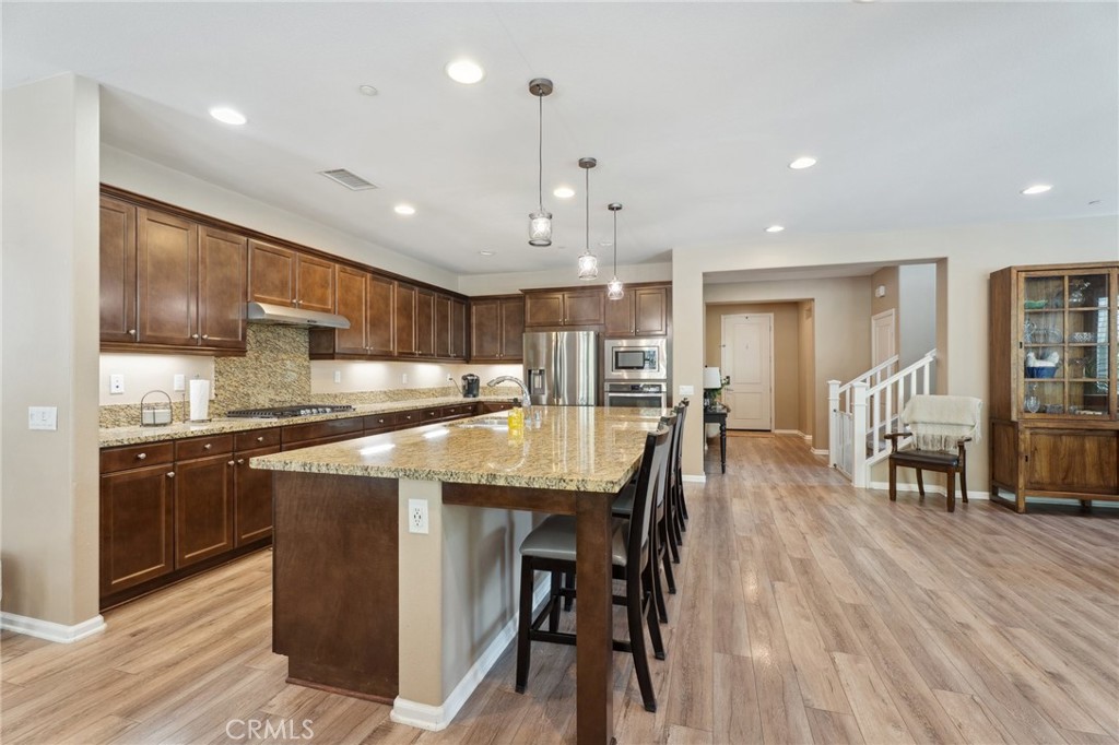 11266 Hutton Road Corona, CA 92883 - Photo 2 of 33 a kitchen with stainless steel appliances kitchen island granite countertop a table chairs refrigerator and sink
