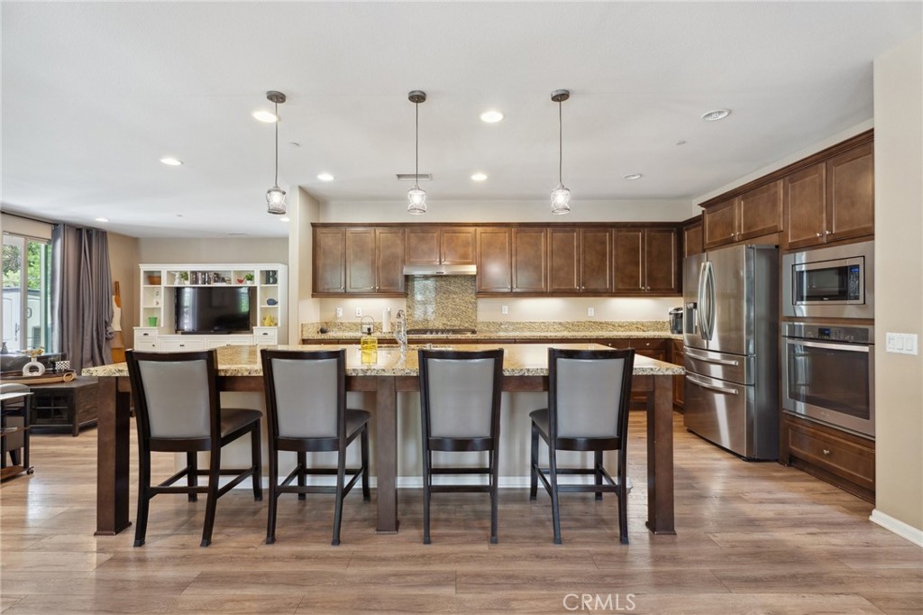 11266 Hutton Road Corona, CA 92883 - Photo 27 of 33 a kitchen with stainless steel appliances granite countertop a dining table chairs refrigerator and sink