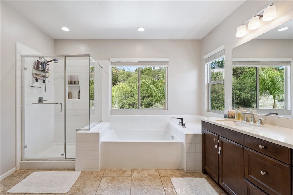 11266 Hutton Road Corona, CA 92883 - Photo 6 of 33 a bathroom with a double vanity sink large mirror and a bathtub