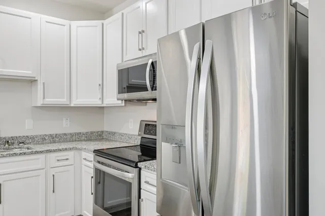 a kitchen with stainless steel appliances granite countertop white cabinets and refrigerator