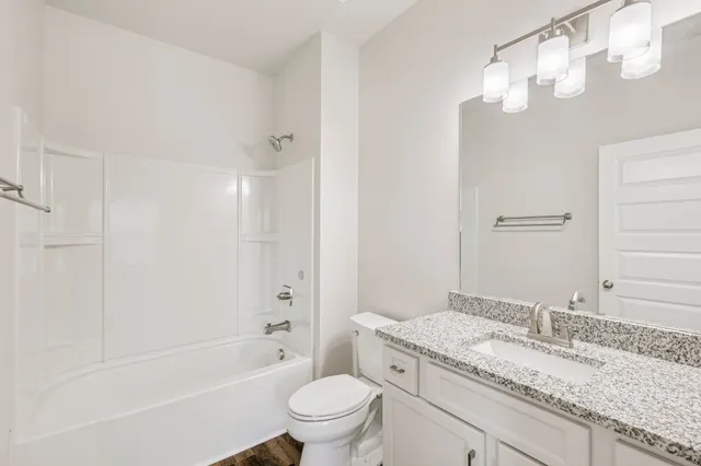 a bathroom with a granite countertop sink a toilet and bathtub