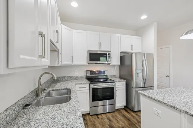 a kitchen with granite countertop a sink stainless steel appliances and white cabinets