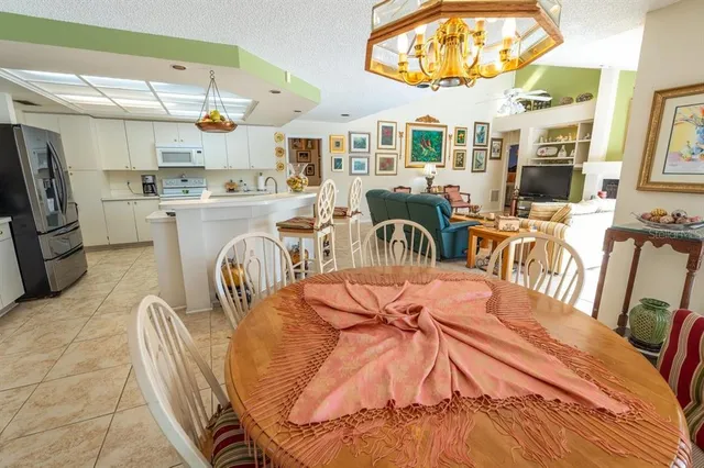 a view of a dining room with furniture a kitchen and chandelier