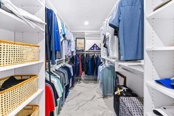 a view of walk in closet with clothes and shoes