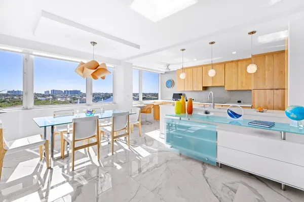 a kitchen with stainless steel appliances kitchen island granite countertop a table chairs in it and a window