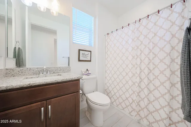 a bathroom with a granite countertop toilet and a sink