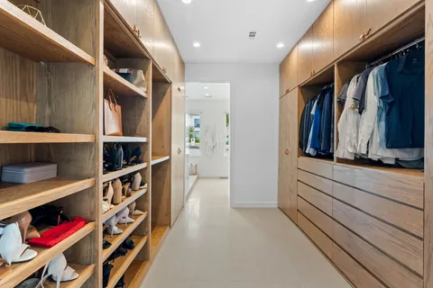 a view of walk in closet with clothes and shoes