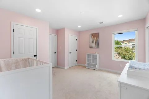 a view of a white house next to a yard with big trees and plants