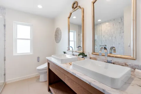 a bathroom with a double vanity sink a mirror and a toilet