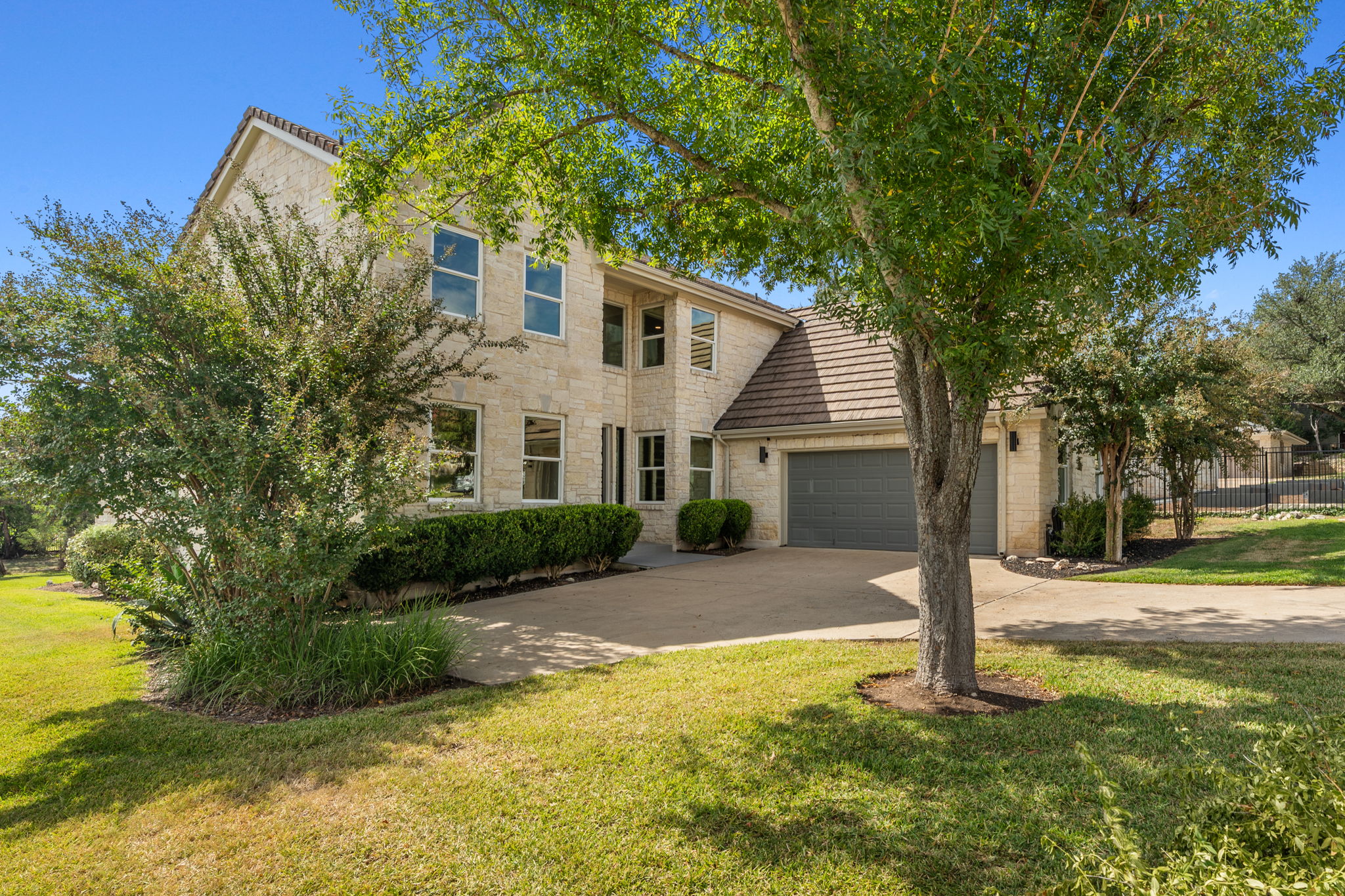 1 Sparrowglen Lane Austin, TX 78738 - Photo 27 of 36 a view of a white house next to a yard with big trees and plants