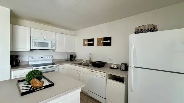 a kitchen with refrigerator a stove a sink and white cabinets