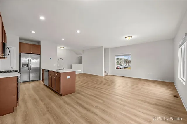 a large kitchen with stainless steel appliances a large counter top and a wooden floors