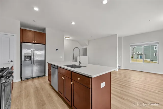 a kitchen with a sink a refrigerator and wooden floor
